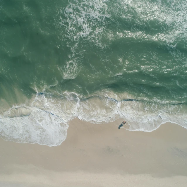 a person riding a surfboard on top of a sandy beach, pexels contest winner, minimalism, helicopter view, turbulent sea, 4k image”, a green