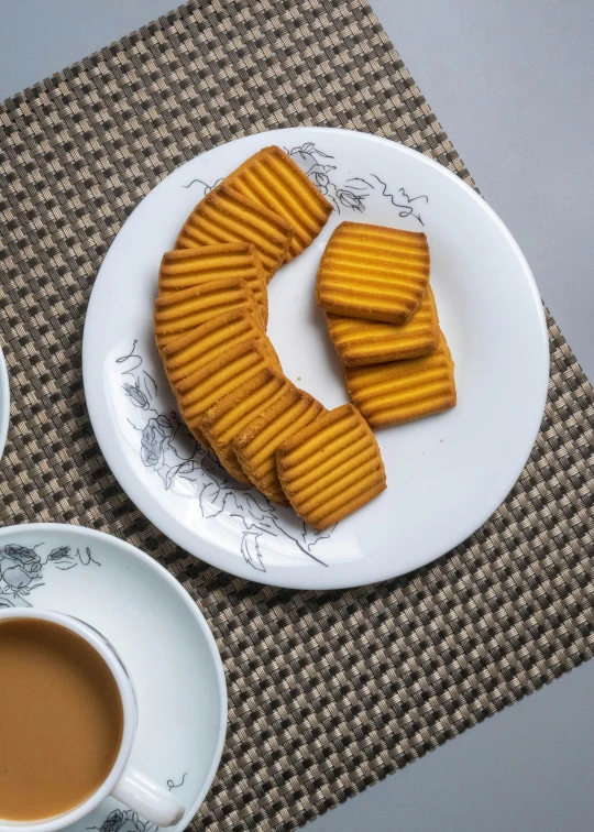 a white plate topped with cookies next to a cup of coffee, inspired by Tang Di, dau-al-set, honey ripples, cheddar, hd quality, square lines