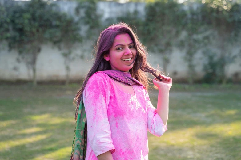 a woman that is standing in the grass, holi festival of rich color, magenta shirt, ameera al taweel, wearing a tie-dye shirt