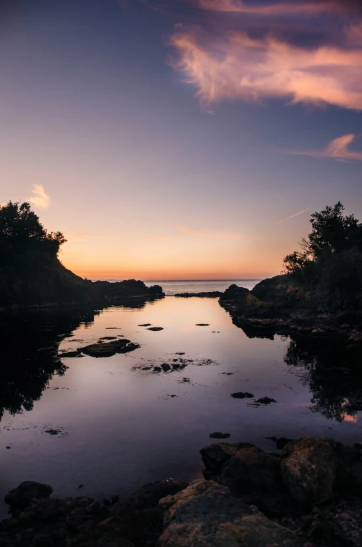 a body of water surrounded by rocks and trees, by Roar Kjernstad, looking out at a sunset, next to the reflecting ocean, skye meaker, harbor