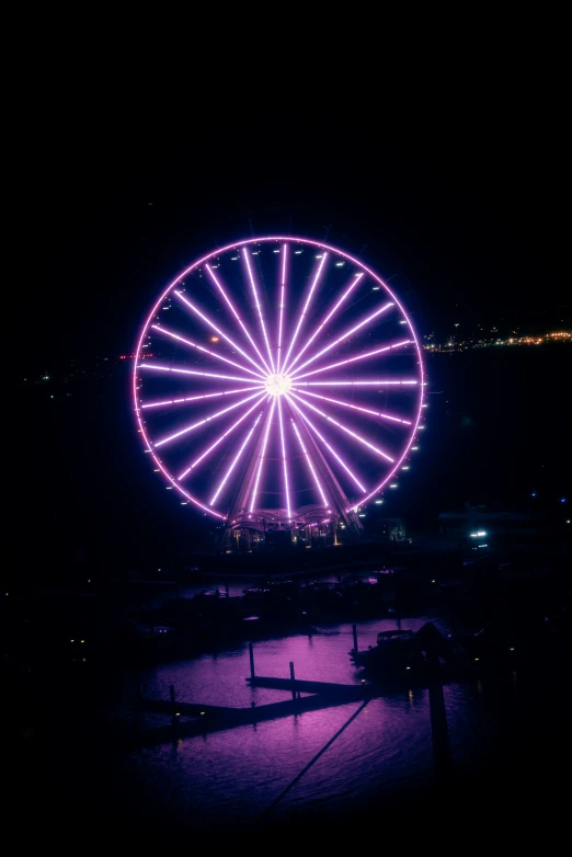 a ferris wheel lit up at night next to a body of water, pink and purple, drone photograpghy, trending on imagestation, lightshow