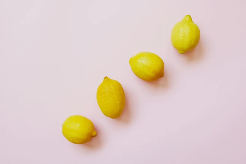 a group of lemons on a pink surface, by Carey Morris, trending on pexels, minimalism, 🐿🍸🍋, pale yellow wallpaper, food, minimalist lines