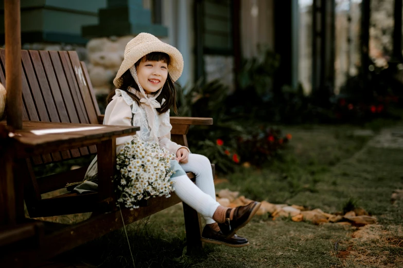 a little girl sitting on top of a wooden bench, inspired by Cui Bai, pexels contest winner, straw hat and overcoat, avatar image, cute smile, floral