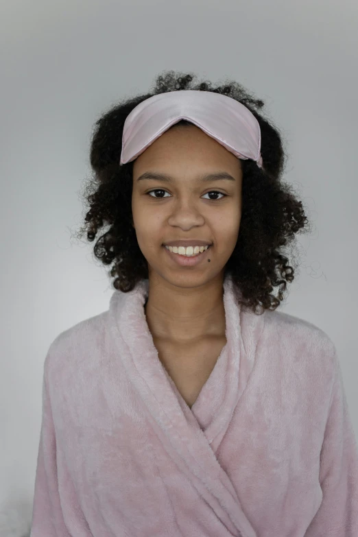 a young girl wearing a pink robe and a pink headband, black teenage girl, photograph taken in 2 0 2 0, skincare, taken in 2022