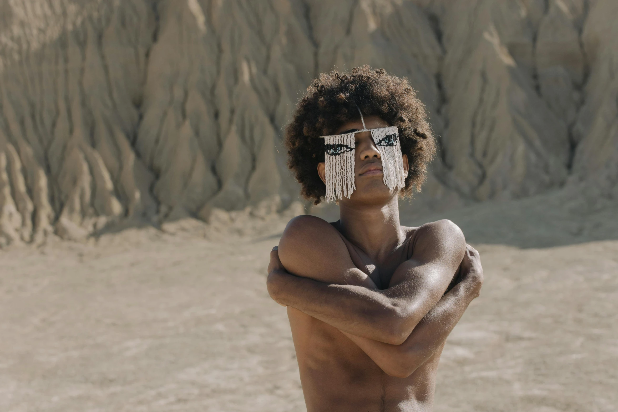 a man with a pair of glasses on his face, an album cover, trending on pexels, afrofuturism, wearing loincloth, full of sand and glitter, 14 yo berber boy, 4 k cinematic still