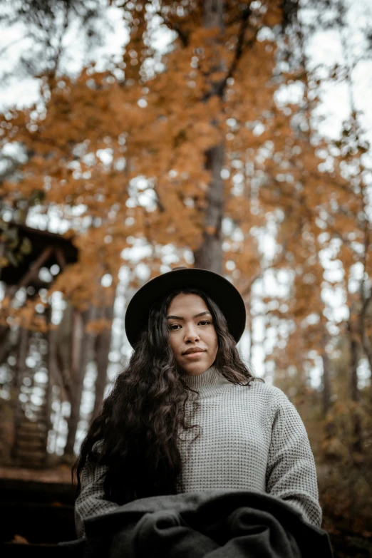 a woman sitting on a bench in the woods, a portrait, pexels contest winner, with hat, mixed race woman, ((portrait)), female with long black hair