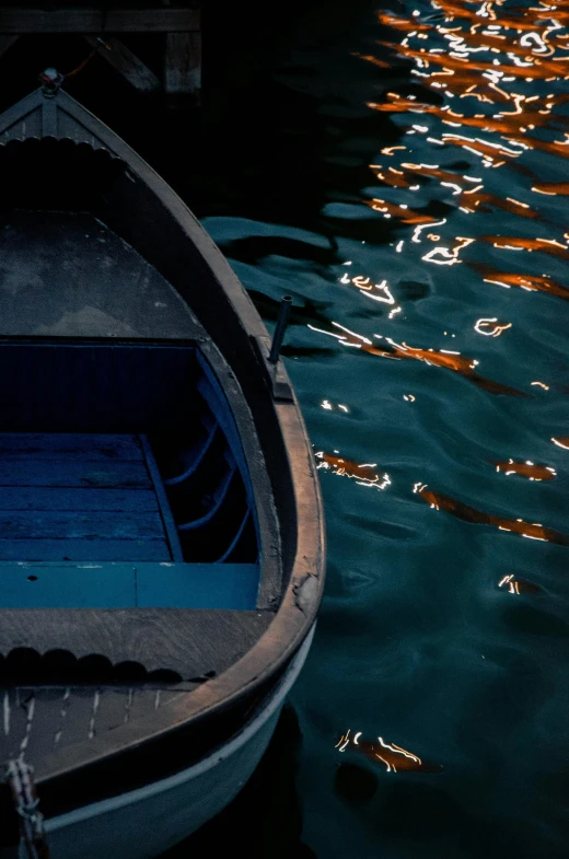 a small boat sitting on top of a body of water, by Eglon van der Neer, pexels contest winner, amber and blue color scheme, dark dingy, middle close up composition, side light