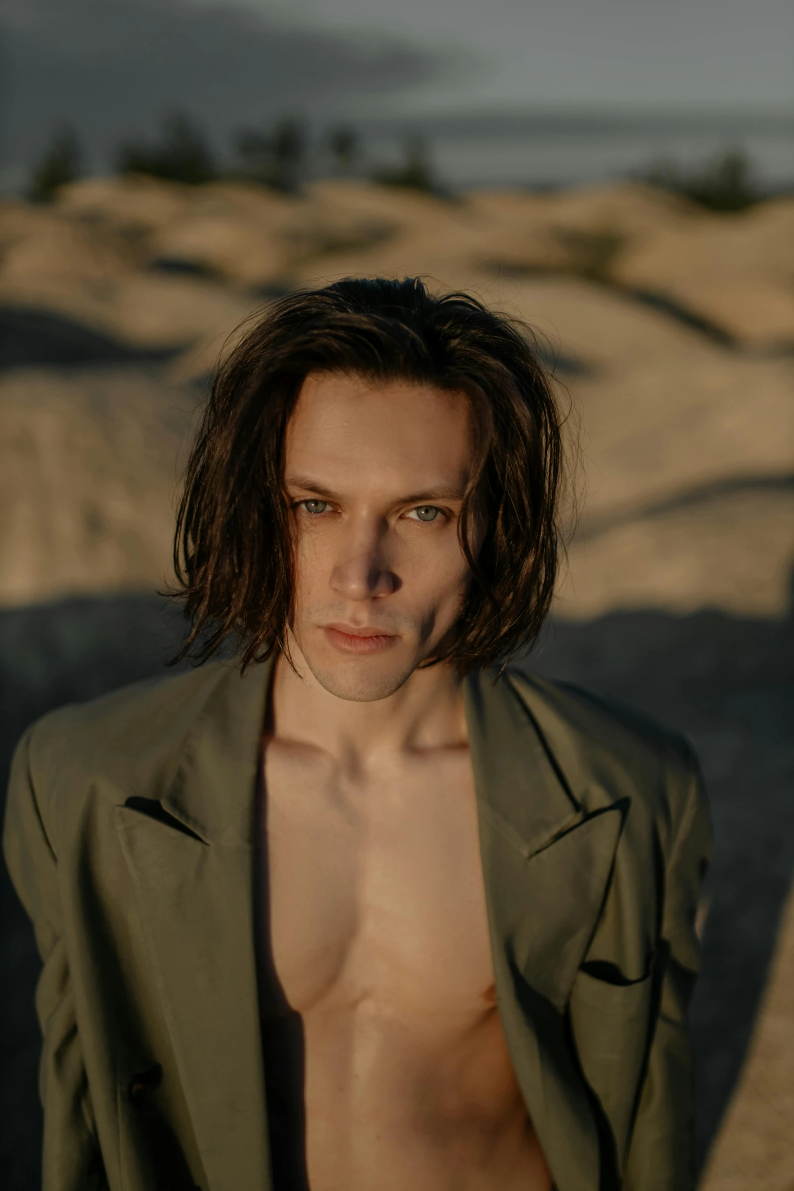 a shirtless man standing on top of a sandy beach, an album cover, inspired by Eugene Leroy, unsplash, bauhaus, billie eilish as loki, handsome male vampire, headshot photo, maxim sukharev
