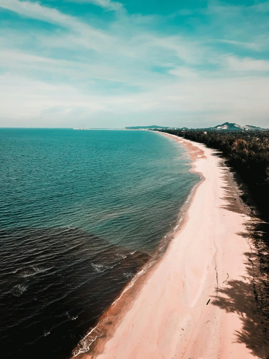 a large body of water next to a sandy beach, a colorized photo, by Adam Marczyński, pexels contest winner, pink, wide high angle view, hd footage, taken on iphone 14 pro