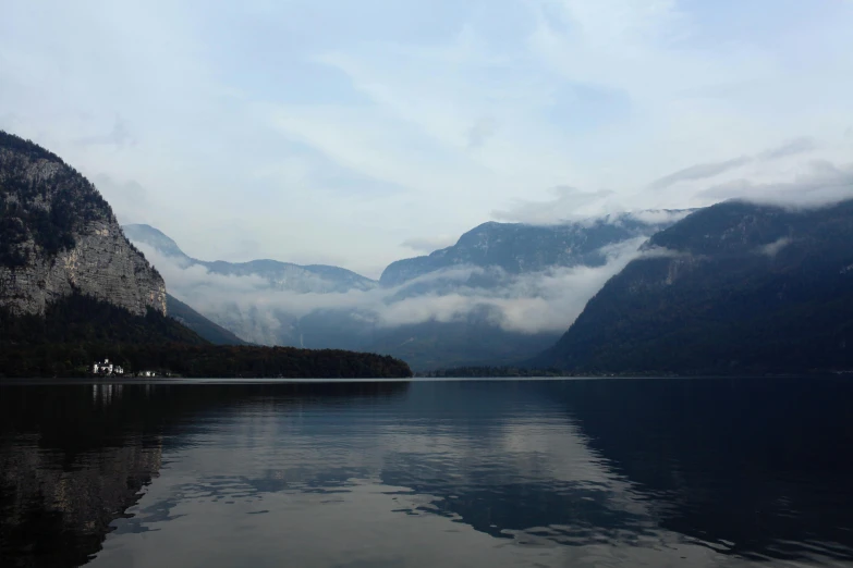 a body of water with mountains in the background, by Emma Andijewska, pexels contest winner, grey mist, autum, southern european scenery, foil