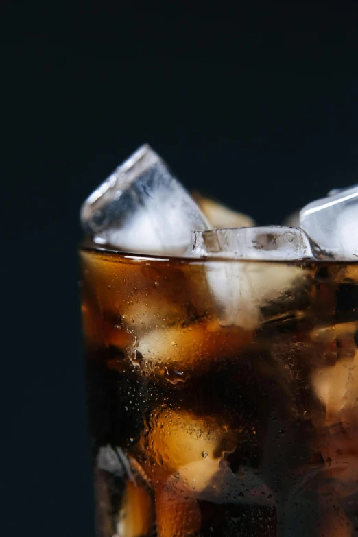 a close up of a glass of soda with ice, trending on unsplash, photorealism, deep black, ignant, high quality photo, made of drink