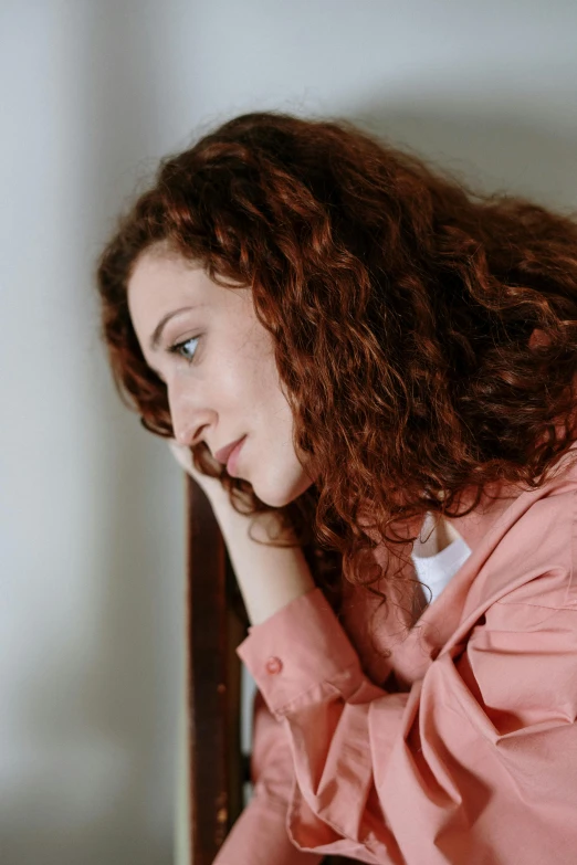 a woman sitting in front of a laptop computer, inspired by Nan Goldin, trending on pexels, renaissance, brown curly hair, sad man, hr ginger, wearing a pink hoodie