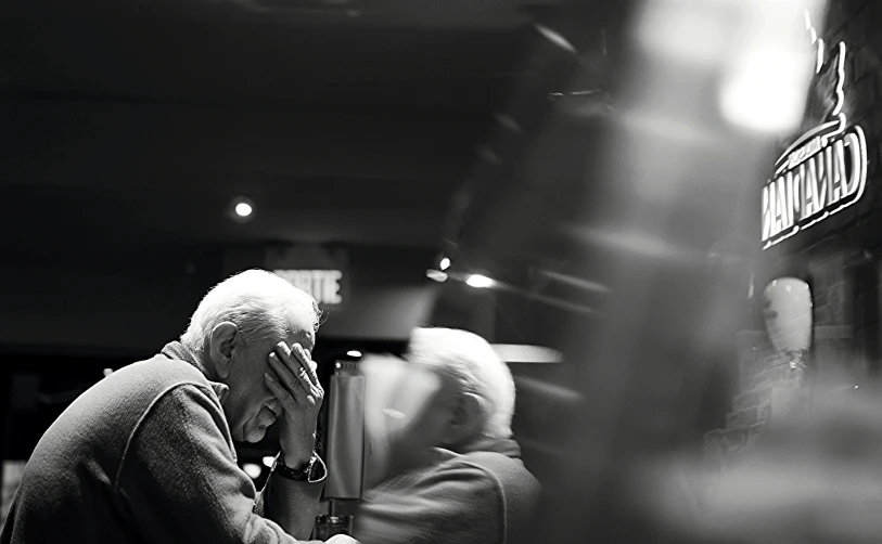 a man sitting at a table talking on a cell phone, a black and white photo, by Matija Jama, two old people, comforting, sitting at a bar, heaven