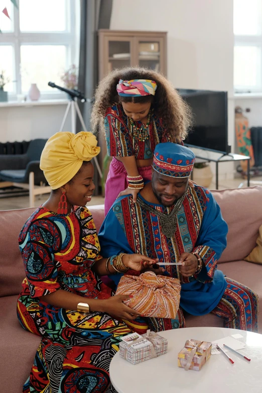 a group of people sitting on top of a couch, pexels contest winner, afrofuturism, somali attire, giving gifts to people, ( ( theatrical ) ), husband wife and son