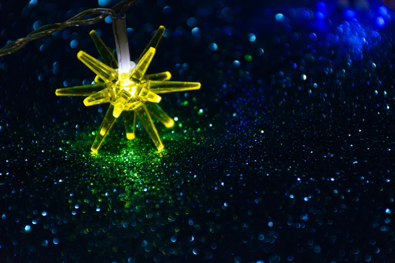 a close up of a string of lights on a table, michilin star, blue and yellow lighting, spiky, green sparkles