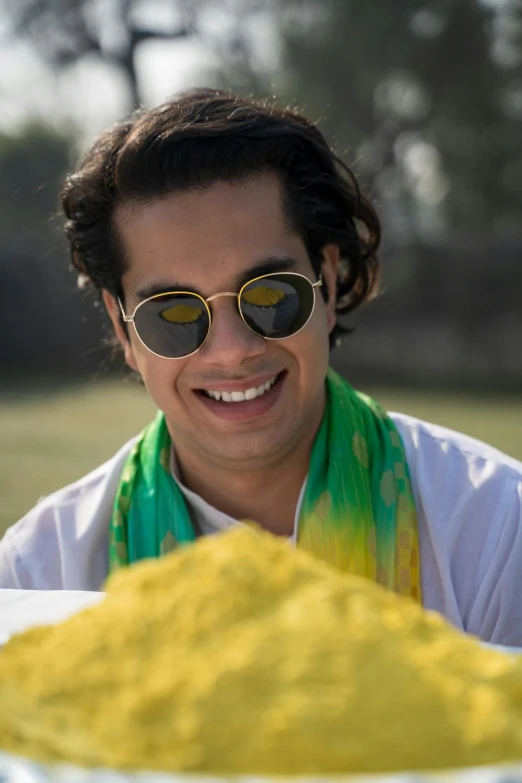a man holding a bowl of yellow powder, inspired by Jitish Kallat, avan jogia angel, bangladesh, having fun in the sun, portrait image