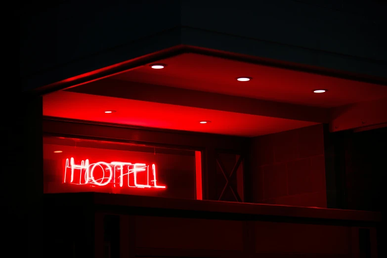 a red neon sign hanging from the side of a building, by Daniël Mijtens, pexels contest winner, motel, well lit, hell, neon standup bar