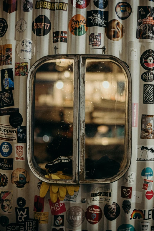 a window with lots of stickers on it, a picture, by Jacob Toorenvliet, pexels contest winner, mirror texture, inside a bar, kombi, industrial aesthetic