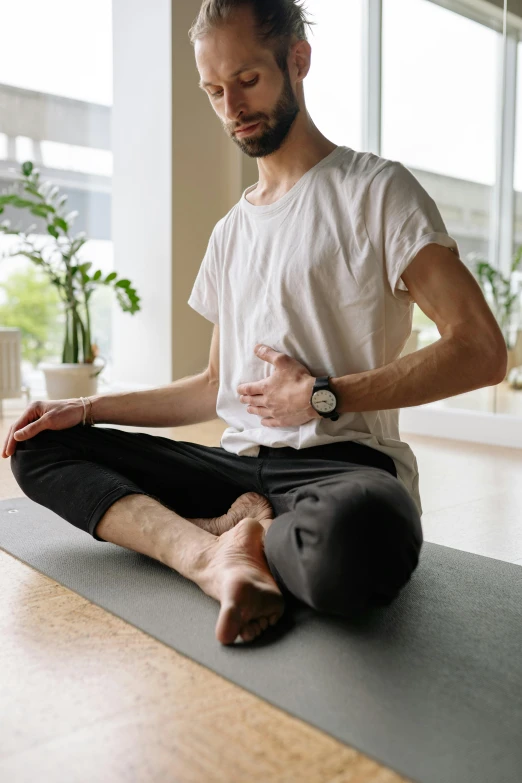 a man sitting on a yoga mat holding a baby, hard breathing, wearing pants and a t-shirt, debilitation, heart rate