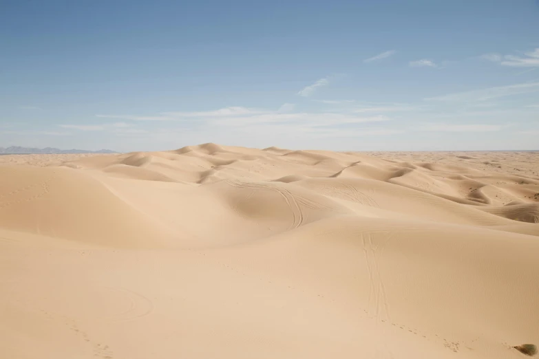 a person riding a horse in the desert, from afar, dunes, colour photograph, tan