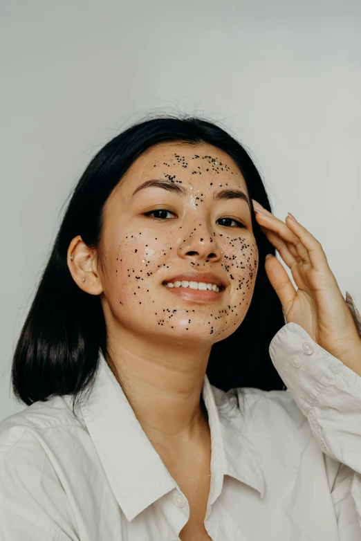 a woman with black spots on her face, trending on pexels, joy ang, black tar particles, official product photo, grey