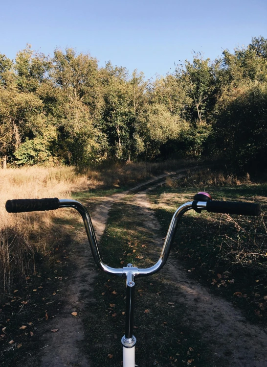 a bicycle parked on the side of a dirt road, profile image, at a park, creepy vibe, first-person view