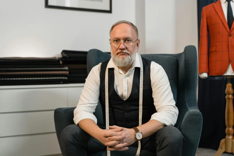 a man sitting in a chair next to a mannequin, inspired by William John Thomson, unsplash, portrait of professor sinister, office clothes, ian david soar, professional profile photo