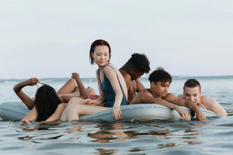 a group of people floating on top of a body of water, by Carey Morris, trending on pexels, sadie sink, with a white complexion, diverse ages, teenager hangout spot
