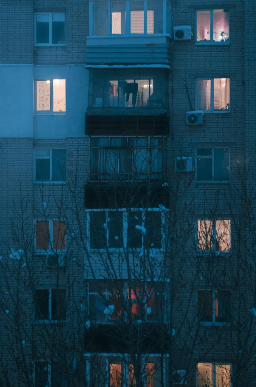 a tall building with lots of windows lit up at night, inspired by Elsa Bleda, pexels contest winner, hyperrealism, soviet suburbs, cold scene, late morning, still from film