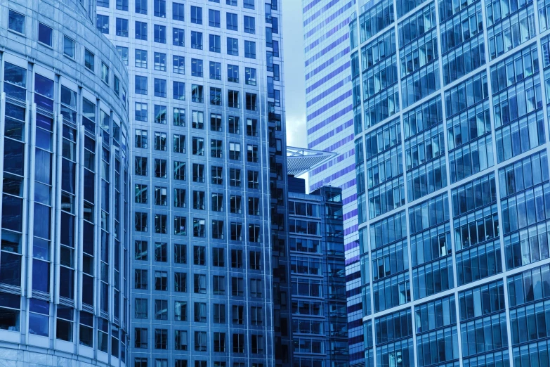 a group of tall buildings next to each other, pexels, modernism, vibrant but dreary blue, corner office background, high - detailed, glazed