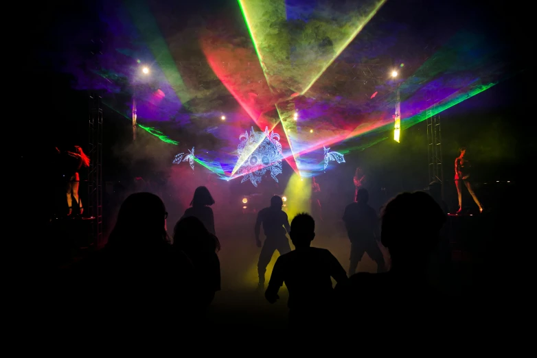 a group of people standing on top of a stage, a hologram, by Joe Bowler, unsplash contest winner, interactive art, goblins partying at a rave, made of lasers, inside a circus tent, taken in the late 2010s