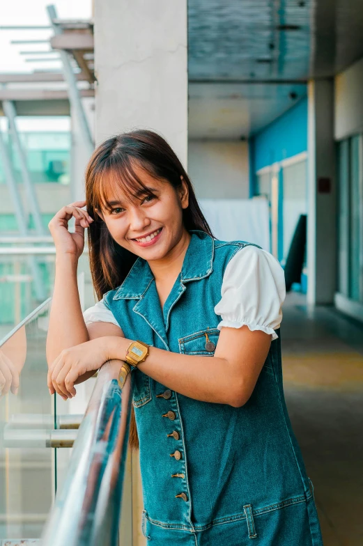 a woman leaning on a railing in a building, by Robbie Trevino, wearing a cute top, south east asian with round face, student, wearing denim