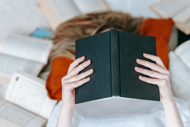 a person laying on a bed reading a book, pexels contest winner, private press, holding books, laying on her back, avatar image, frontal shot