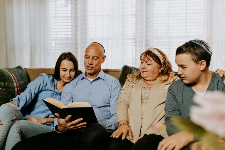 a family sitting on a couch reading a book, a portrait, by Carey Morris, pexels, biblical image, te pae, group sit at table, high quality screenshot