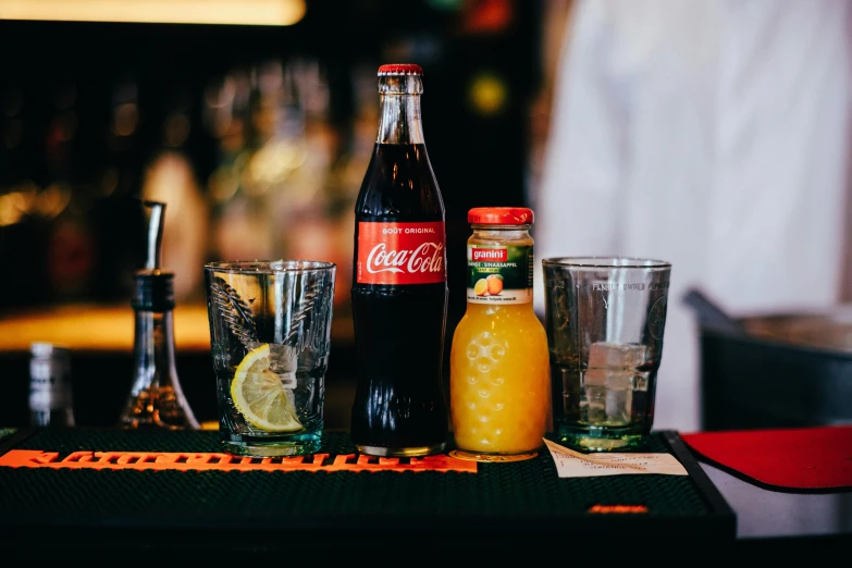 a group of drinks sitting on top of a bar, coca cola bottle, fan favorite, daily specials, black and orange