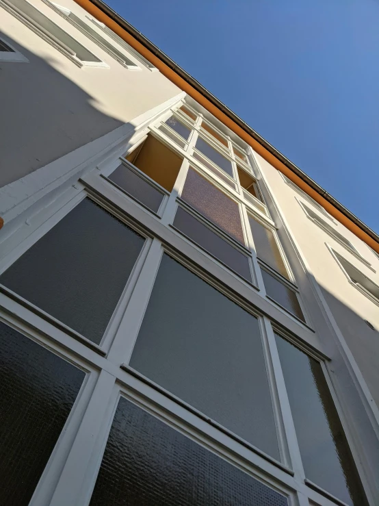 a tall white building with lots of windows, inspired by Albert Paris Gütersloh, unsplash, bauhaus, french door window, strong contrasting shadows, taken on iphone 1 3 pro, nvidia raytracing demo))))