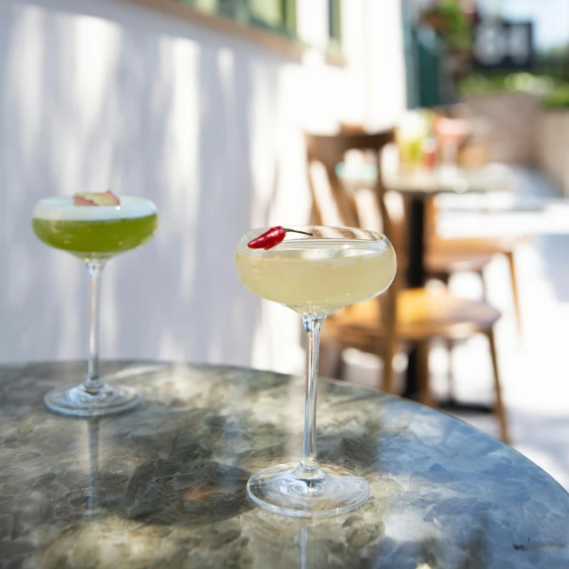 two cocktail glasses sitting on top of a table, green terrace, all marble, hollywood standard, thumbnail