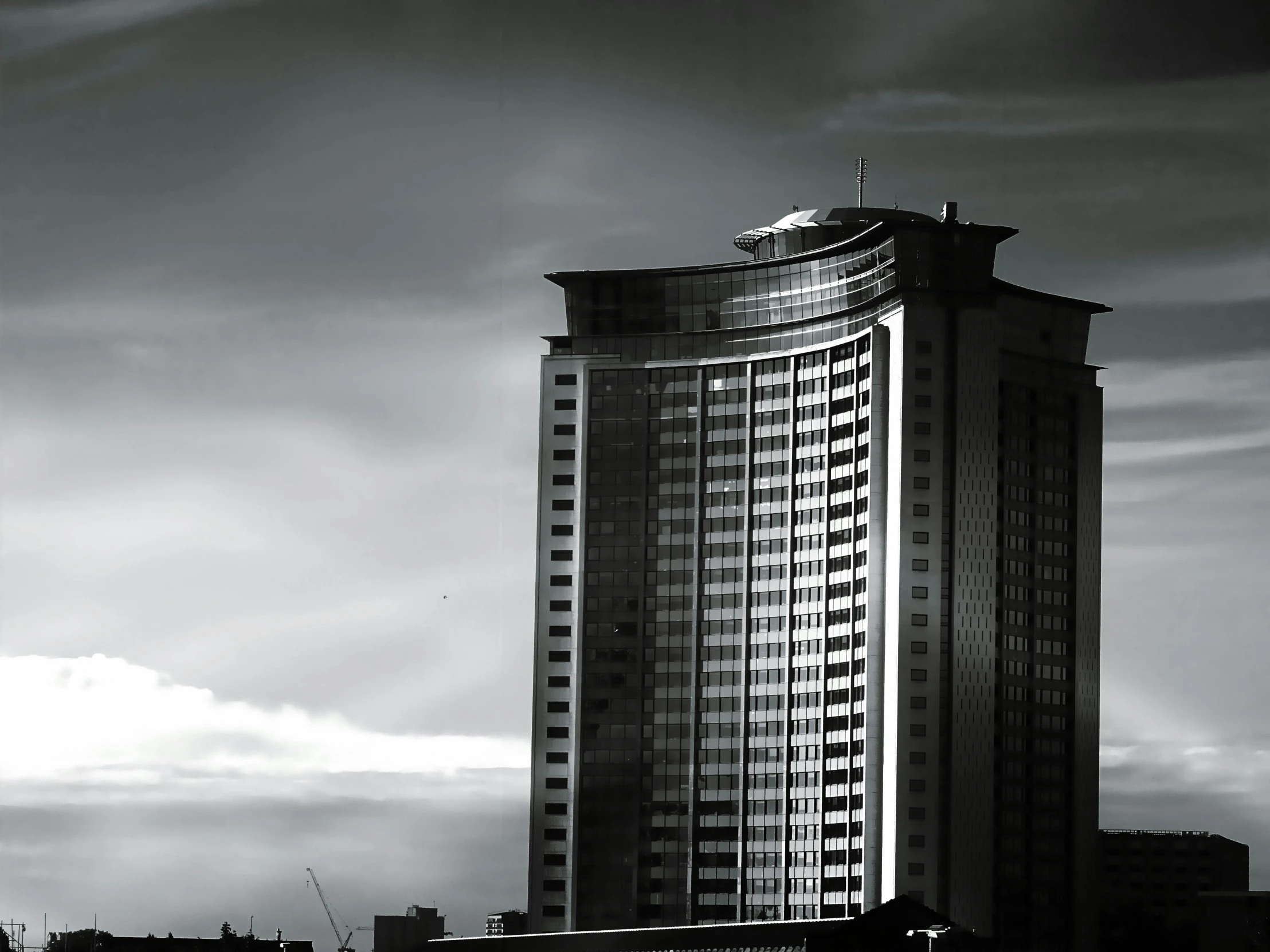 a black and white photo of a tall building, a black and white photo, by Andrei Kolkoutine, unsplash, futuristic phnom-penh cambodia, hotel room, dramatic sky, moscow