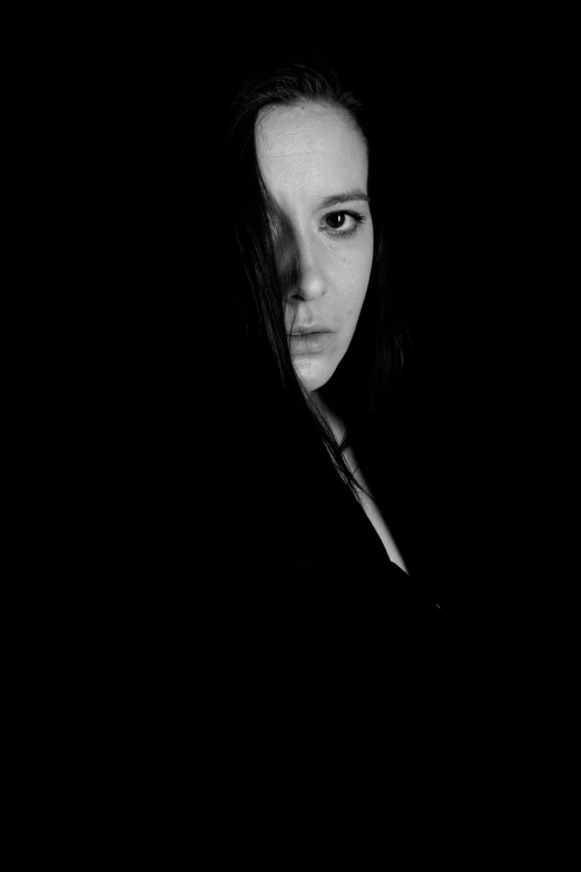 a black and white photo of a woman in the dark, a black and white photo, flickr, dark-hair, & a dark, concerned, wearing a dark hood