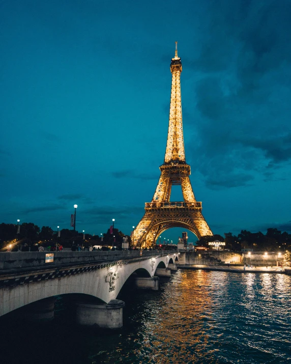 the eiffel tower is lit up at night, an album cover, pexels contest winner, lgbtq, building along a river, thumbnail, vintage photo