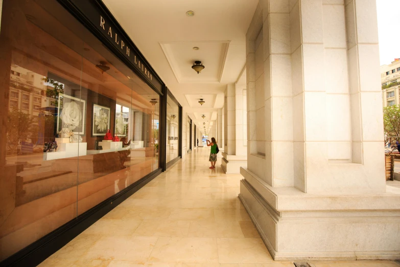 a couple of people walking down a long hallway, inspired by Raúl Martínez, hyperrealism, bulgari, shop front, all marble, exterior photo