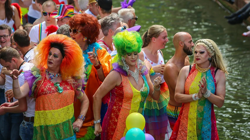 a group of people that are standing in the water, by Jan Tengnagel, pexels, renaissance, pride parade, colorful dress, lush surroundings, in a row