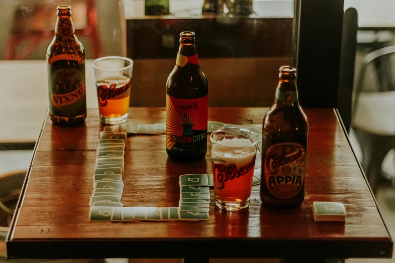 a group of beer bottles sitting on top of a wooden table, sitting at a table, with neon signs, red stripe, guide