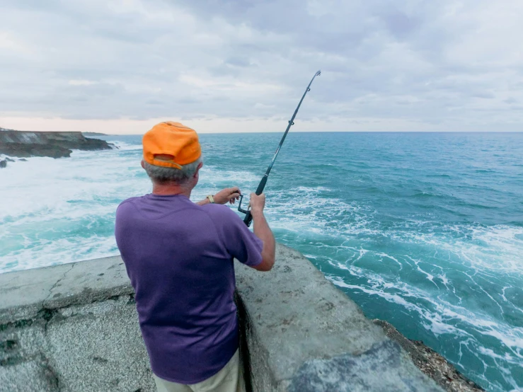 a man standing on top of a rock next to the ocean, fishing pole, marsden, profile image