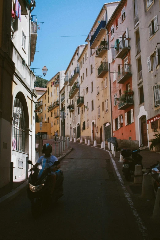 a person riding a motorcycle down a narrow street, a picture, unsplash, renaissance, cannes, sunfaded, low quality footage, city on a hillside