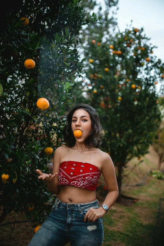 a woman standing in front of an orange tree, trending on pexels, belly button showing, blowing bubblegum, croptop, smoking