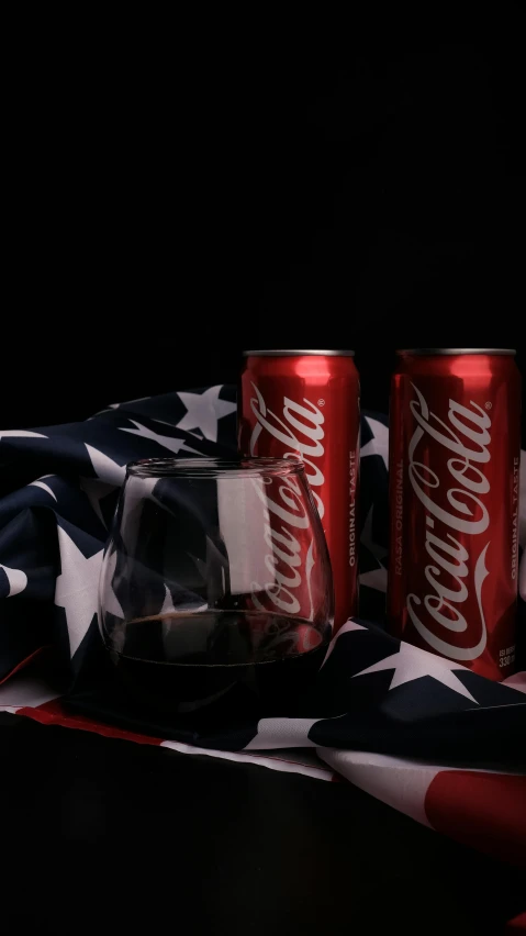 two cans of coke sitting on top of an american flag, a still life, unsplash, hyperrealism, red wine, high quality photo, hyperrealistic n- 4, on black background