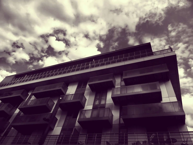 a black and white photo of a tall building, unsplash, brutalism, 🪔 🎨;🌞🌄, old sepia photography, sky!!!, balconies