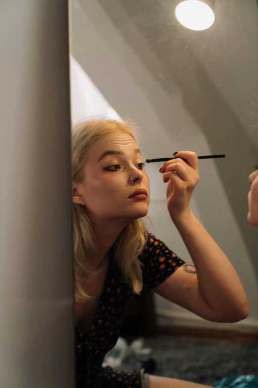 a woman is doing makeup in front of a mirror, by Lee Gatch, reddit, photorealism, young blonde woman, elle fanning), vhs colour photography, black eyeliner