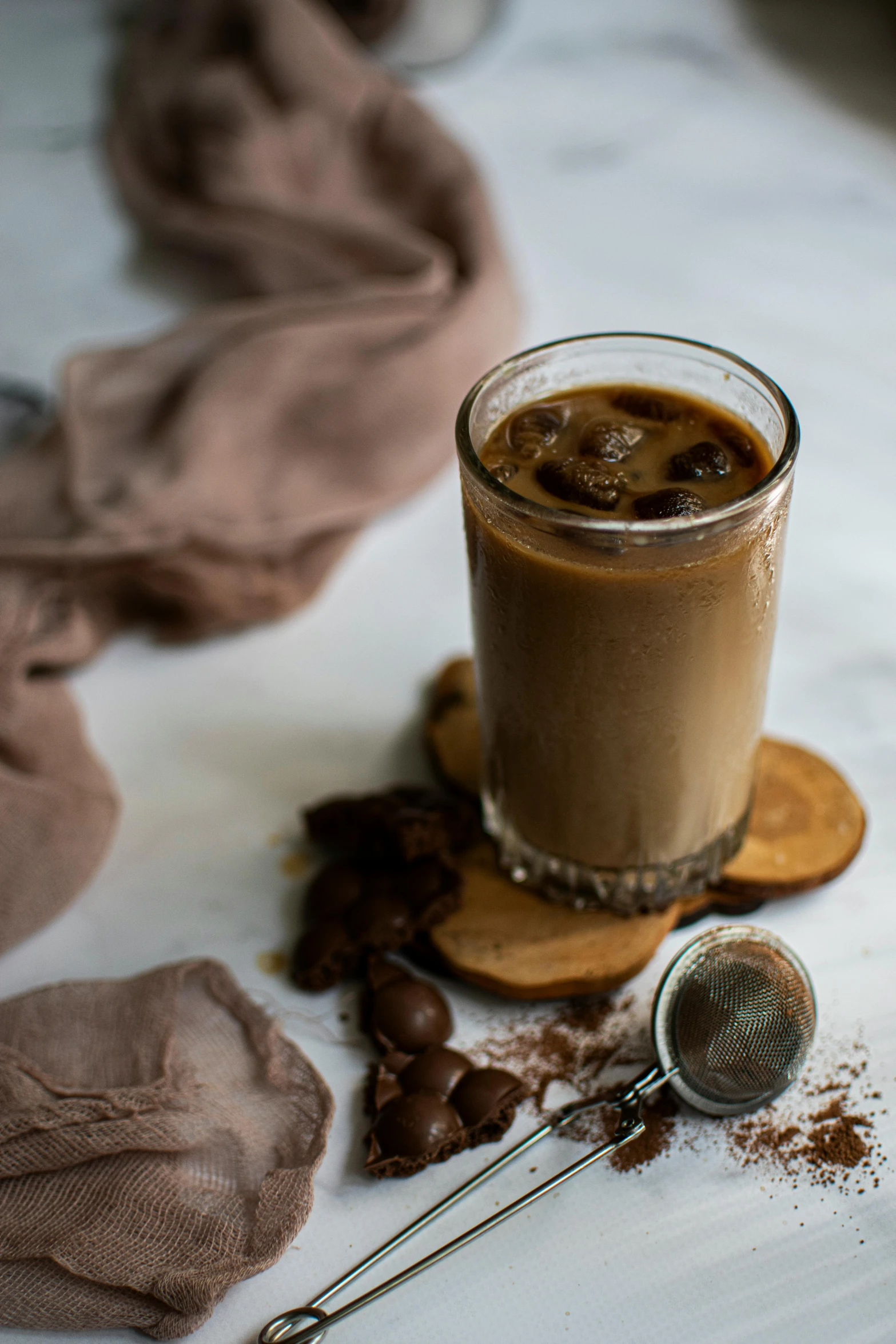 a glass of coffee sitting on top of a table, chocolate, icy, onyx, chiffon